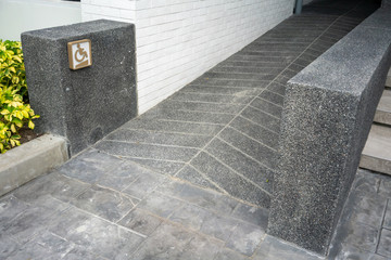 Ramped access, using wheelchair ramp with information sign on wall