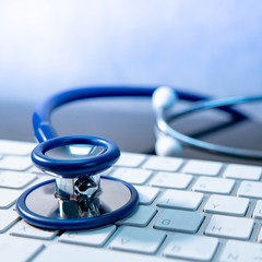 Medical science technology concept. Blue stethoscope on white modern keyboard on doctor desk....