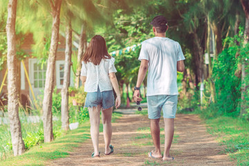 Couple walking and taking photos under the pine trees in the public park.