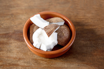 Tropical Coconut pieces in a ceramic bowl  on wooden background. Coco nut top view. Healthy food concept