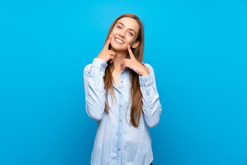 Fototapeta premium Young woman over isolated blue background smiling with a happy and pleasant expression