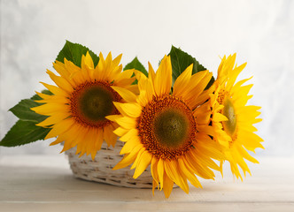Autumn still life with sunflowers in basket. Autumn arrangement with flowers on a white wooden table.