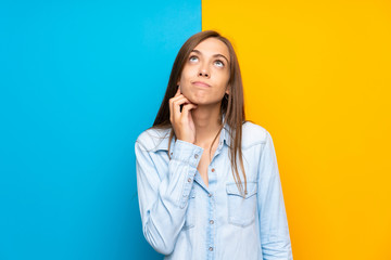 Young woman over colorful background thinking an idea