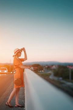 Young Woman In Orange Dress On Bridge