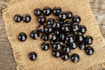 Black currants on burlap and wooden background.Top view. Flat lay pattern