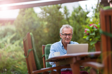 Senior man working on laptop in the garden