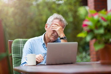 Obraz premium Senior man looking stressed while working on laptop 