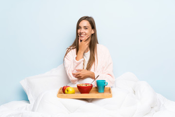 Young woman in dressing gown with breakfast laughing