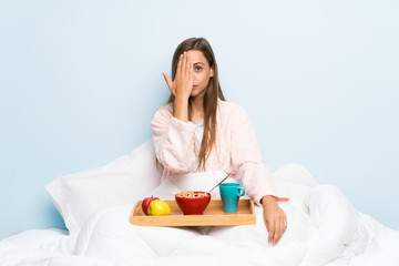 Young woman in dressing gown with breakfast covering a eye by hand