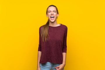 Young woman over isolated yellow background shouting to the front with mouth wide open