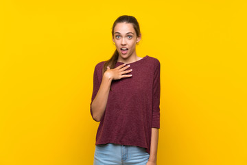Young woman over isolated yellow background surprised and shocked while looking right