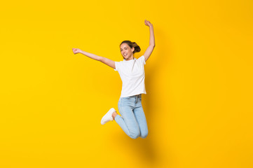 Fototapeta Young woman jumping over isolated yellow wall obraz