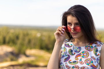 The girl in pink glasses on the background of the forest