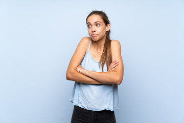 Young woman over isolated blue background making doubts gesture while lifting the shoulders