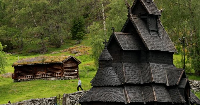 Borgund, Norway. People Walking Near Famous Norwegian Landmark Stavkirke An Old Wooden Triple Nave Stave Church In Summer Day. Zoom, Zoom out. Close View, Details
