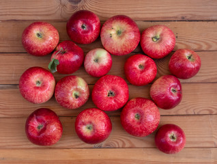 Red apples lie on a wooden background.