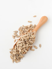 Top view of natural shelled organic sunflower seeds on wooden spoon isolated on white background. It often eaten as a snack.  The seeds contain vitamin E. Food and snack concept.