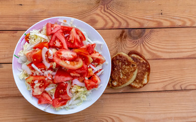 Sliced tomatoes, onions and cabbage on a plate on the table.