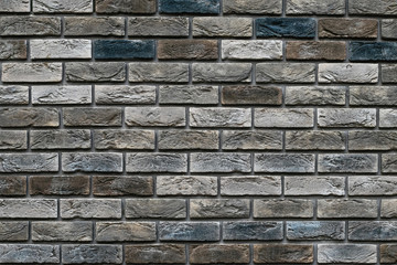 Old weathered brick wall of different colors. Vintage varicolored bricks background. Decorative tile surface. Rough brickwork. Brown and gray pattern, grunge texture. Rough cement wall. Copy space.