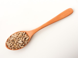 Top view of natural shelled organic sunflower seeds on wooden spoon isolated on white background. It often eaten as a snack.  The seeds contain vitamin E. Food and snack concept.