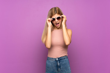 Teenager girl over isolated purple background with glasses and surprised