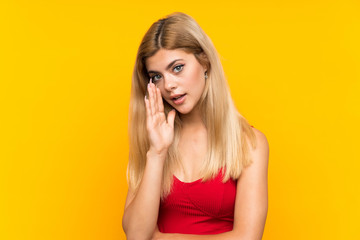 Fototapeta premium Teenager girl over isolated yellow background whispering something