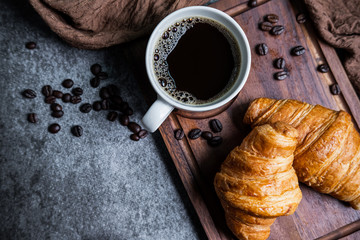 Breakfast with fresh croissants and cup of black coffee on wooden board - Powered by Adobe