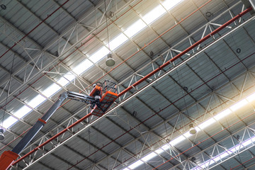 Worker standing on an articulating boom lifts in the factory.
