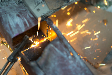 Worker making sparks from welding steel in work place.