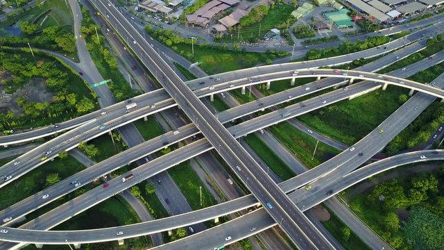 4K. Aerial view of road interchange or highway intersection with busy urban traffic speeding on the road. Junction network of transportation taken by drone.