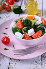Light salad with broccoli, cherry tomatoes and feta cheese in a white ceramic bowl