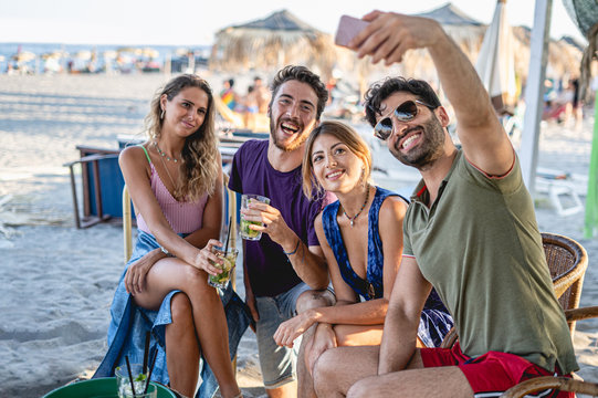 Group of friends on vacation making a selfie on a beach bar. Young people drinking and relaxing in the summertime lifestyle concept