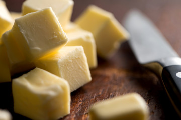 Close up of butter cubes and knife on wooden table