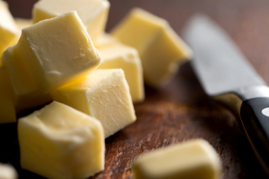 Close up of butter cubes and knife on wooden table