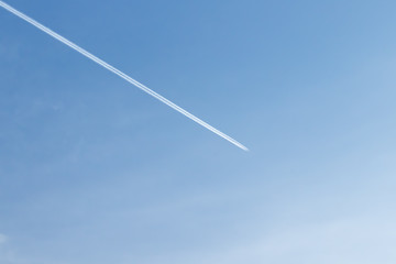 White plane flying high in blue sky