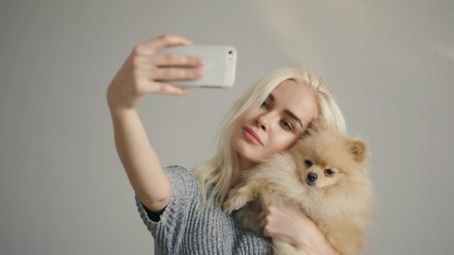 Beautiful Blonde Woman Making Selfie With Her Spitz Isolated On Grey, student girl model posing with mask application with pet