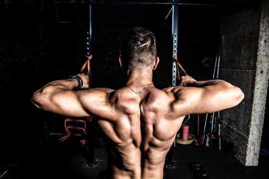 Young strong man workout training back muscles in the gym dark image