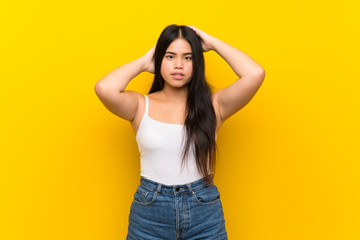 Fototapeta premium Young teenager Asian girl over isolated yellow background frustrated and takes hands on head