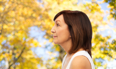 beauty, rhinoplasty and old people concept - profile of senior woman over natural autumn background
