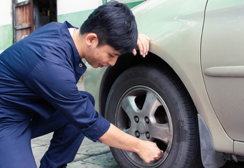 A man is checking tyre in automotive maintenance service center