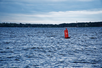 Red buoy drifts in the swell against a blue sky.