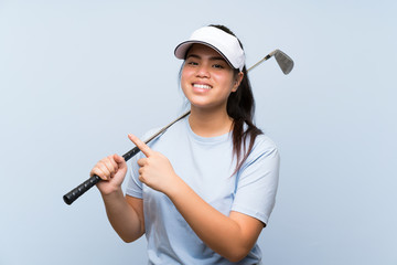 Young golfer Asian girl over isolated blue background pointing to the side to present a product