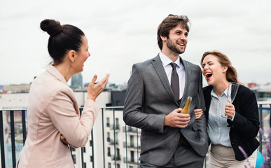 A group of joyful businesspeople having a party outdoors on roof terrace in city.