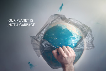 A man breaks a garbage bag which is wrapped globe of planet Earth. The concept of ecology and pollution of the surrounding environment. Tint and slogan