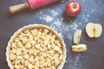 Traditional homemade apple pie and ingredients on wooden background for autumn holiday