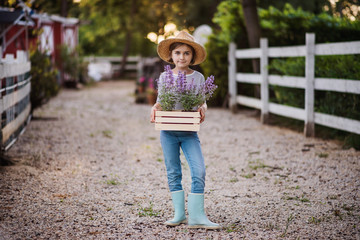 Obraz premium A front view of small girl standing outdoors on family farm, holding plants.