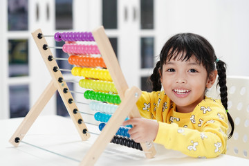 Cute Asian little kid girl playing with abacus at home. Smart child learning to count. learning, classroom, lesson concept. 