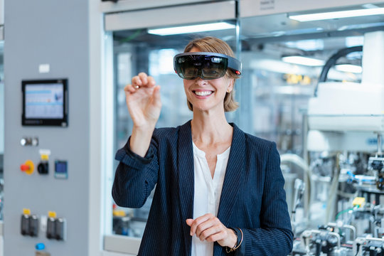 Smiling businesswoman wearing AR glasses in a modern factory