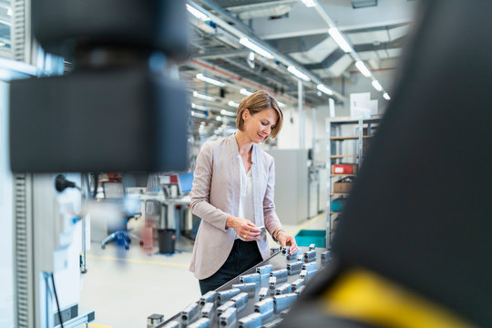 Businesswoman examining workpieces in a modern factory hall