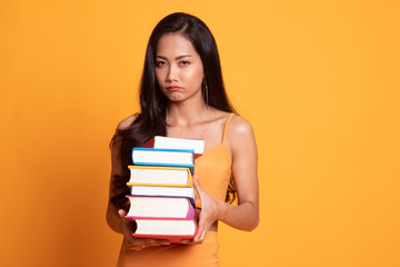 Unhappy young Asian woman studying  with may books.